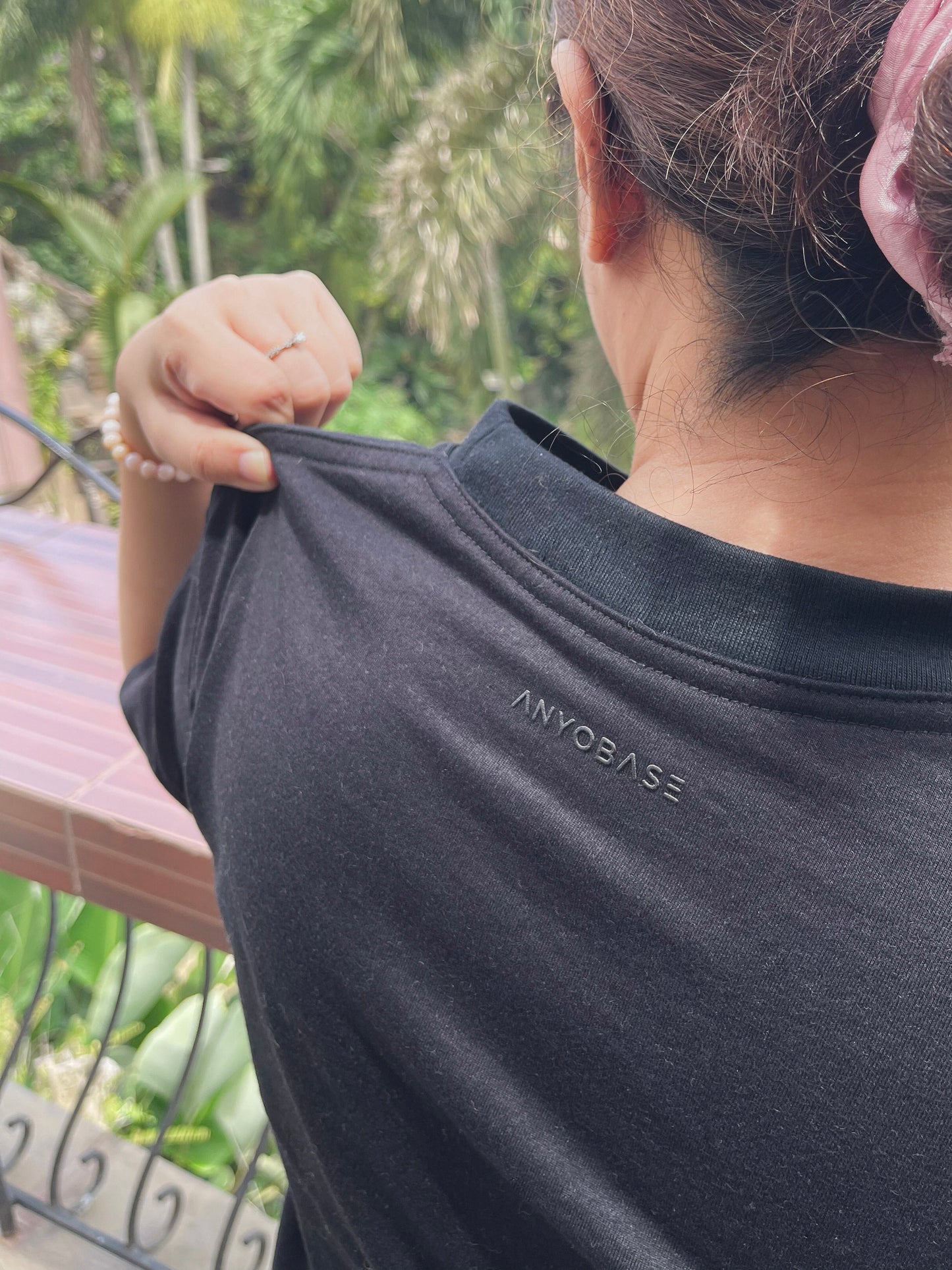 ANYOBASE Core Tee in Black showing the tonal back-neck logo.