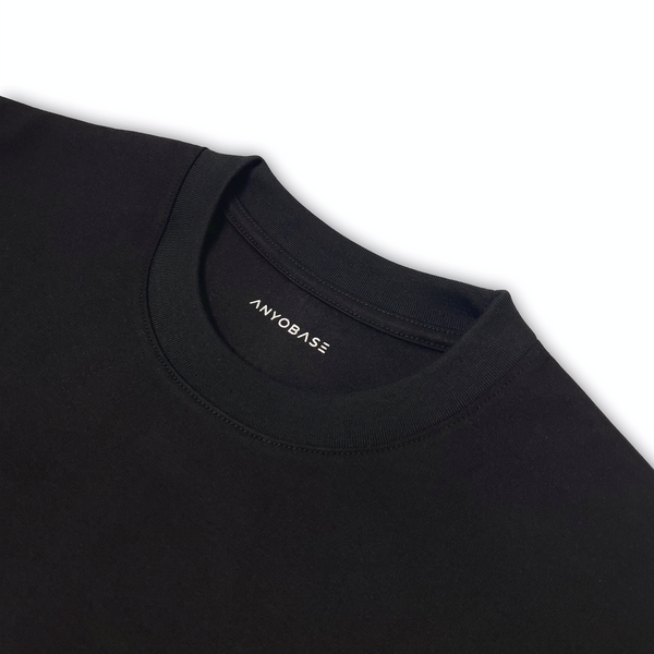 Close-up of the black ANYOBASE T-shirt featuring a ribbed collar and printed inner neck logo.